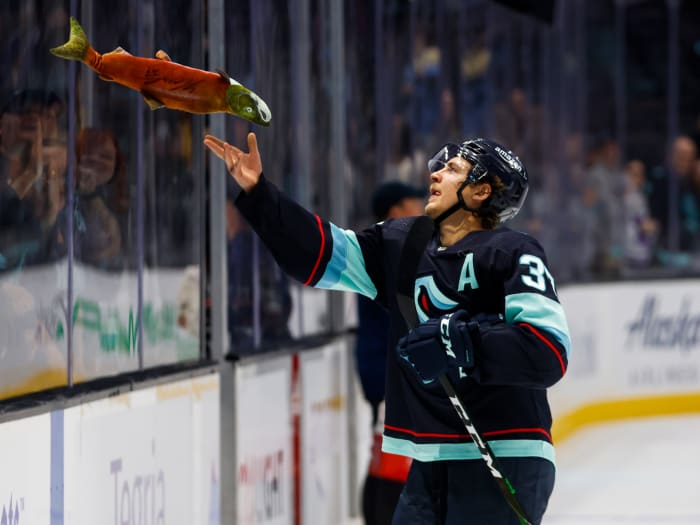 Seattle Kraken center Yanni Gourde (37) tosses a toy sockeye salmon to fans following a 4-0 victory against the Vancouver Canucks.
